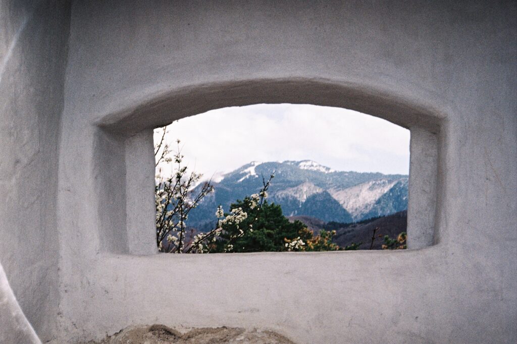 The Carpathians framed by an old wall on the way up to Rasnov fortress, captured on 35mm film.